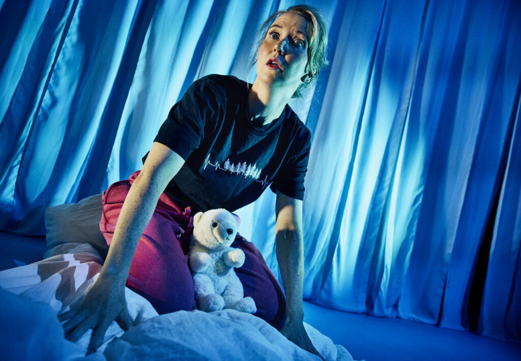 Molly (Kristine Lauritzen) tør ikke falde i søvn, hun frygter skovbrande, oversvømmelser og at fremtiden ikke findes i morgen. Mollys Mikrokosmos. Teater Zebu og Nørregaards Teater. Foto: Emilia Therese